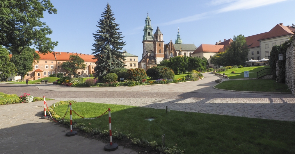 dziedziniec zewnętrzny, droga i chodnik prowadzący w stronę zamku, trawniki i klomby , z tyłu budynki na wzgórzu: administracyjne i  katedra